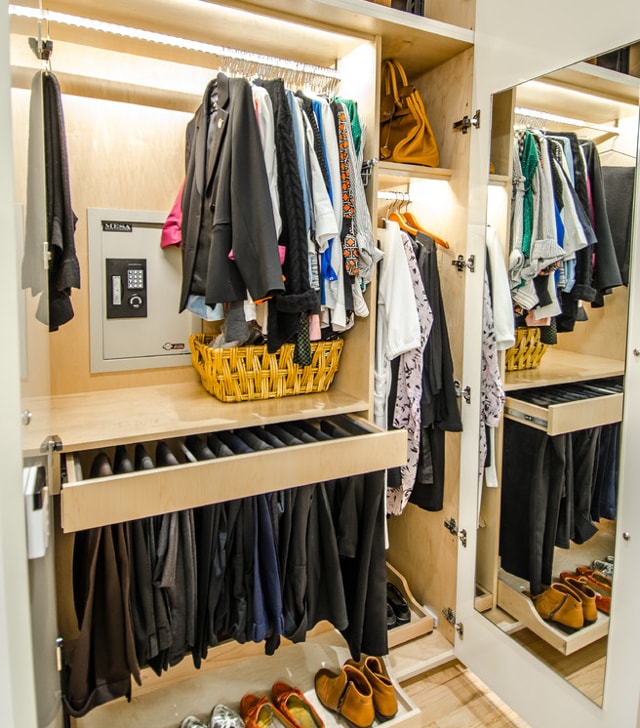 Встраиваемый сейф в гардеробной, спрятанный в закрытом шкафу за одеждой.