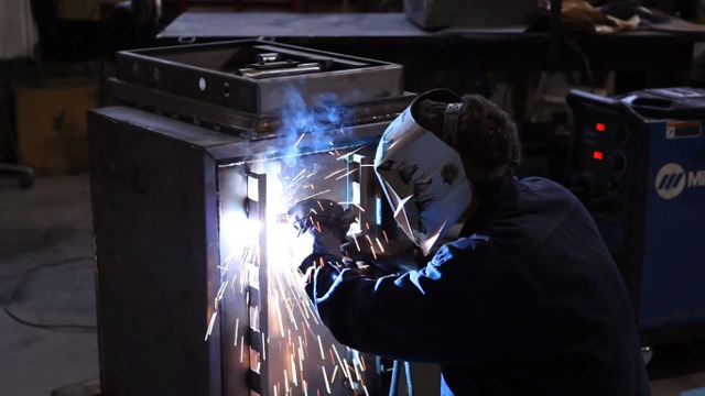 Сварщик приваривает усиленную раму, дверные петли.